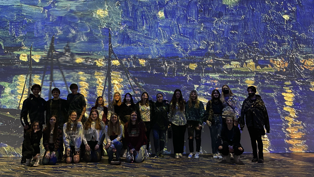 Students stand behind a projected portrait by Van Gogh